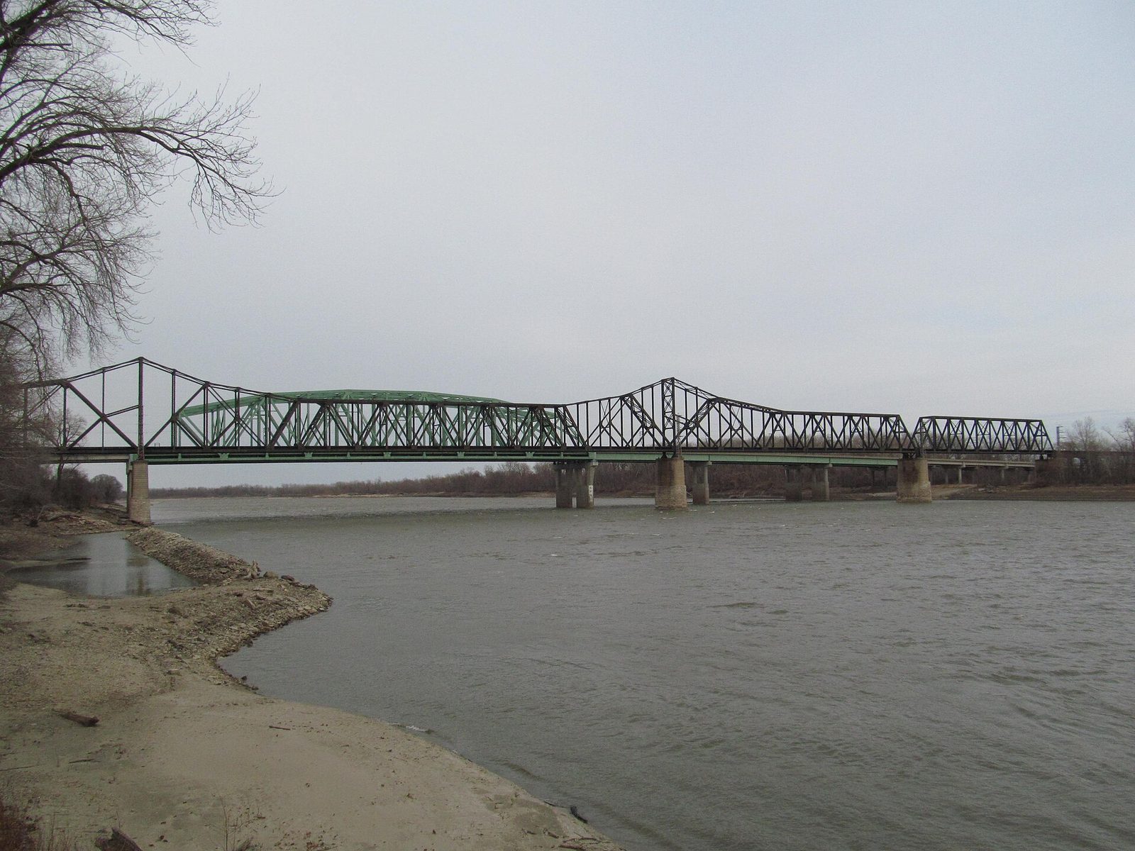 The Wabash railroad truss bridge crossing the gray Missouri River at St. Charles under an overcast late-winter sky, bare trees on the bank